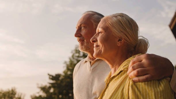 An older couple standing together outdoors at sunset